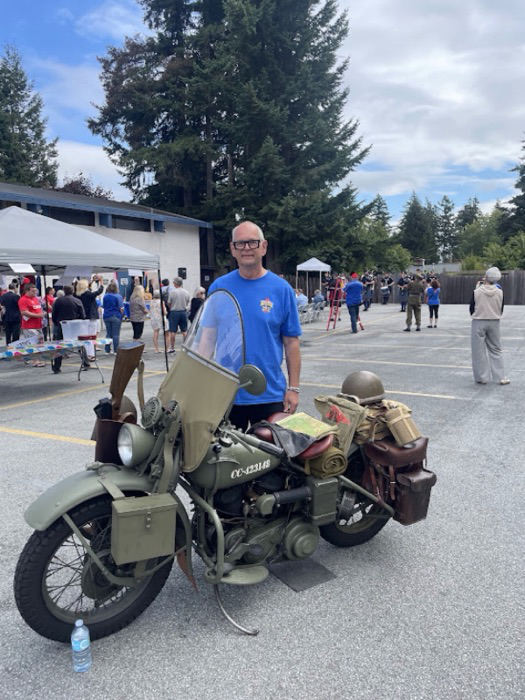 Ernie at a community event beside a vintage motorcycle